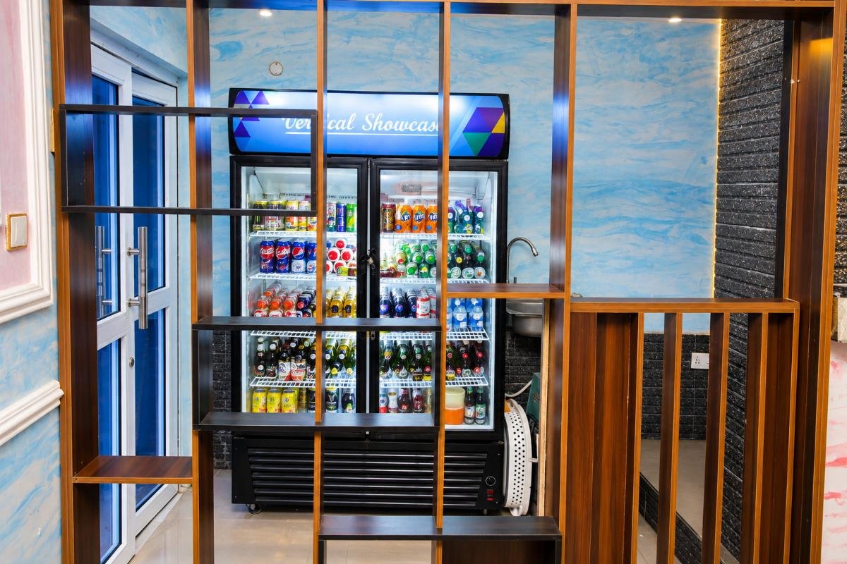 Hotel beverage station with a glass-door drinks refrigerator and selection of chilled beverages at PEB Global Hotel