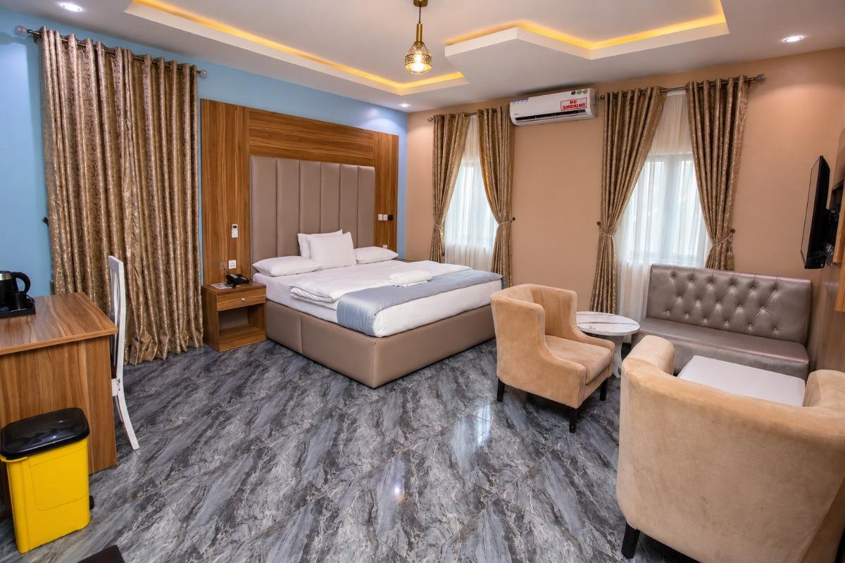 Spacious deluxe hotel room with a king-size bed, lounge seating, TV, air conditioning and elegant interior at PEB Global Hotel