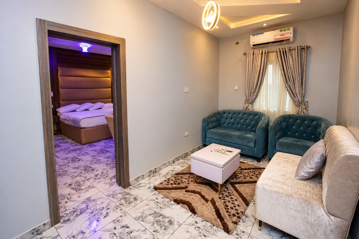 Comfortable hotel mini-suite living area with sofas, coffee table, carpet and adjoining bedroom at PEB Global Hotel